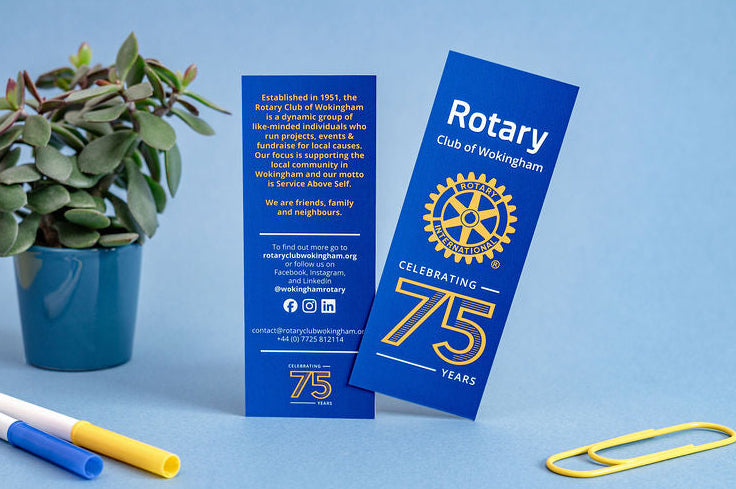 Two blue rotary club bookmarks with a plant and markers on a blue background