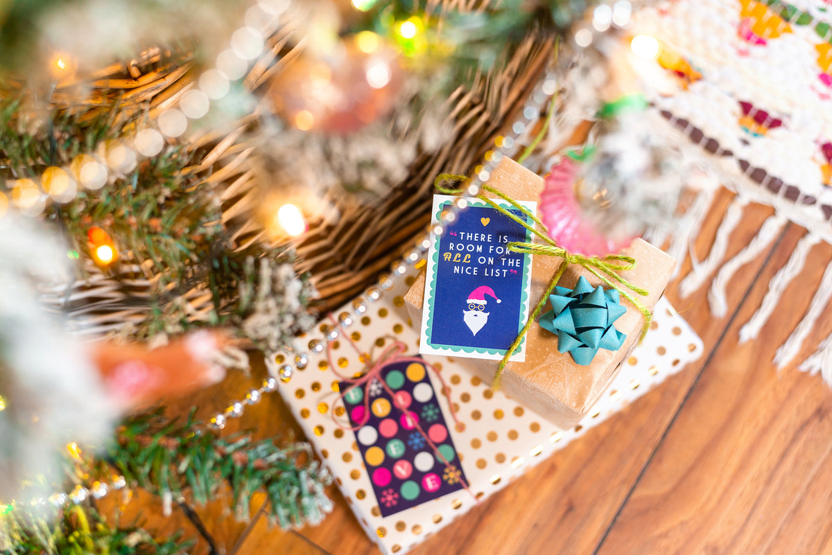 Gifts under a decorated Christmas tree with a card and colorful item.