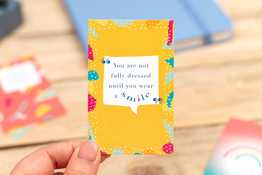 Hand holding a yellow card with a motivational quote on a wooden surface